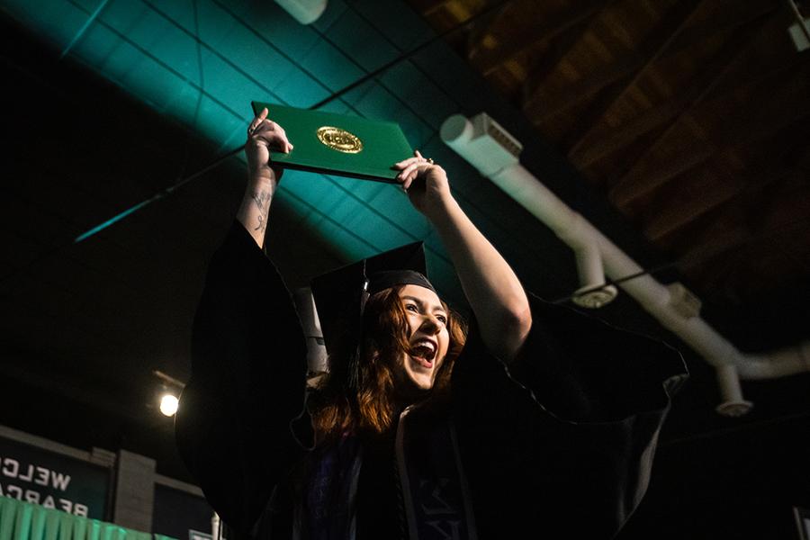 周六，<a href='http://tlaabq.bzga110.com'>威尼斯人在线</a>的一名毕业生在毕业典礼上展示她的毕业证书.